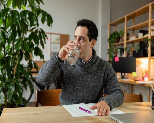 Person drinking water at office desk